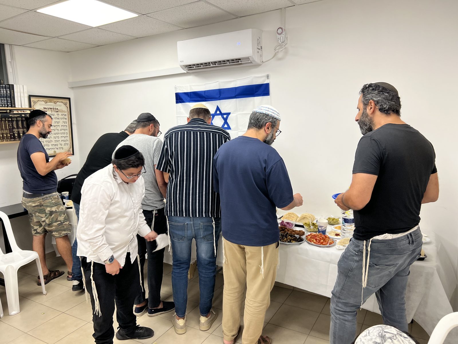 Hommes au buffet sous le drapeau d’Israël lors de la soirée d’accueil des olim