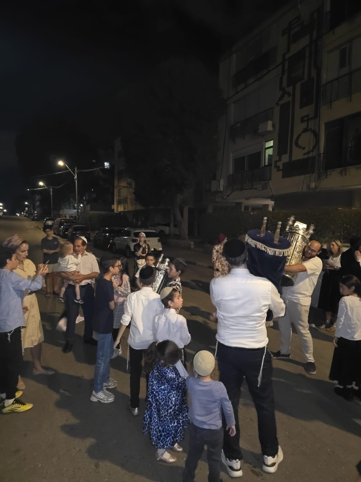 Procession nocturne des Hakafot Chniyot dans la rue, familles autour de la Torah